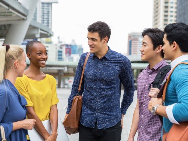 Five people standing in a semi-circle having a conversation.